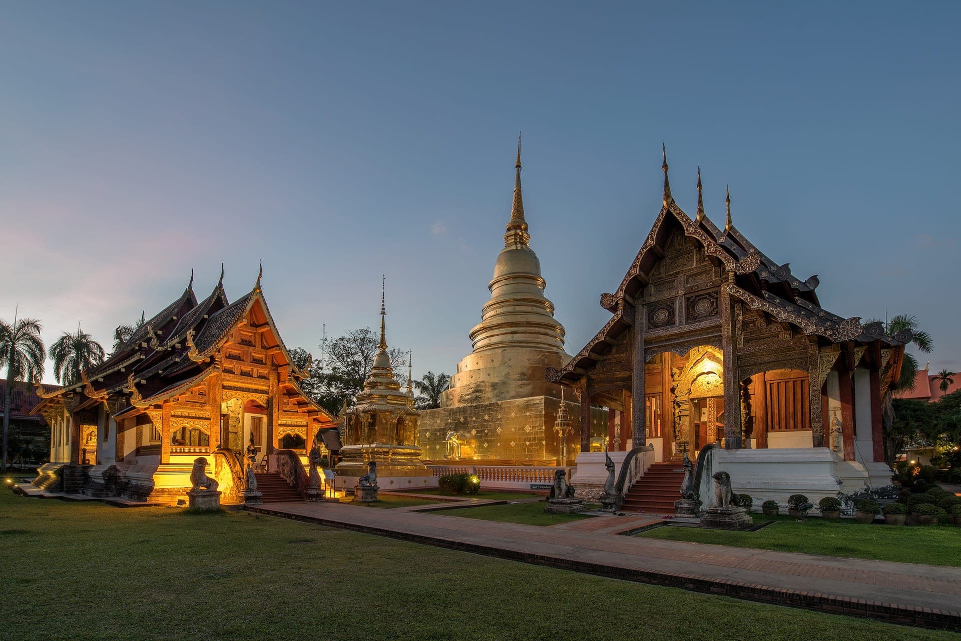 The gilded chedi and carved wooden hall of Wat Phra Singh in Chiang Mai, lit up at dusk