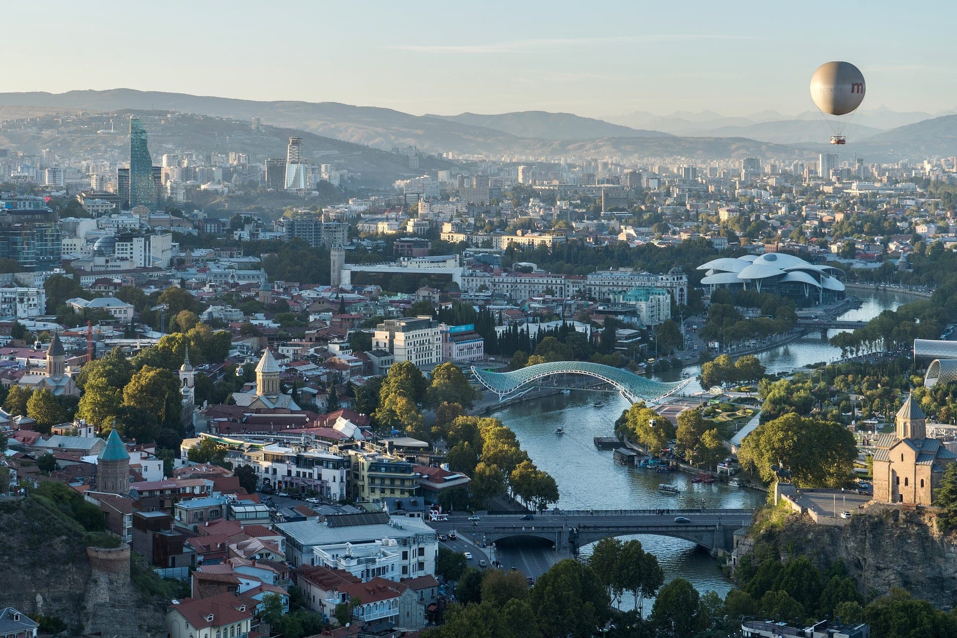 An aerial view over Tbilisi's old town and the Mtkvari river, the city's tethered hot-air balloon floating above the park